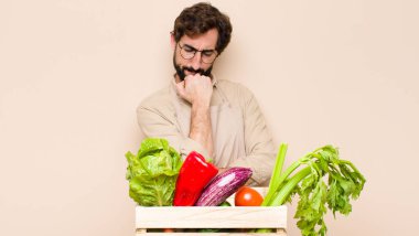 Yeşil bakkal, ciddi, düşünceli ve endişeli hissediyor, elleri çenesine bastırılmış, yan bakıyor