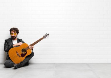 Genç müzisyen kafası karışmış, kafası karışmış, bir sorunu çözmeye çalışıyor ya da gitar, rock 'n roll konseptiyle düşünüyor.