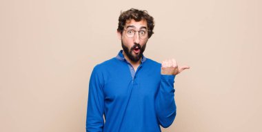 Genç ve yakışıklı adam inançsızlıktan şaşkın şaşkın bakıyor, yan taraftaki objeyi işaret ediyor ve diyor ki vay be, düz duvara karşı inanılmaz.