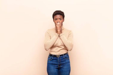 Genç ve güzel siyah kadın endişeli, üzgün ve korkmuş, ağızlarını ellerle kapatmış, endişeli ve berbat görünüyor.