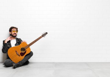 Genç müzisyen kendini stresli, hayal kırıklığına uğramış ve yorgun hisseder. Endişeli ve sorunlu bakışlarıyla gitar, rock 'n roll konseptiyle boynu ovuşturur.