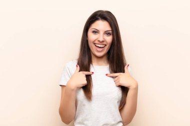 Genç, güzel bir kadın mutlu, şaşırmış ve gururlu hissediyor. Heyecanlı ve şaşkın bir bakışla kendini işaret ediyor.