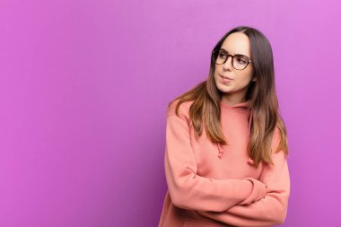 Genç, güzel bir kadın şüphe ediyor ya da düşünüyor, dudağını ısırıyor ve kendini güvensiz ve gergin hissediyor, mor duvara karşı kenardaki boşluğu kopyalamak istiyor.