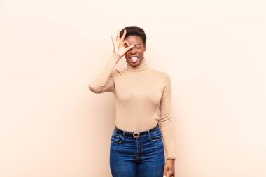 Genç, güzel, siyah bir kadın mutlu bir şekilde gülümsüyor, şakalaşıyor, gözetleme deliğinden bakıyor, sırları gözetliyor.