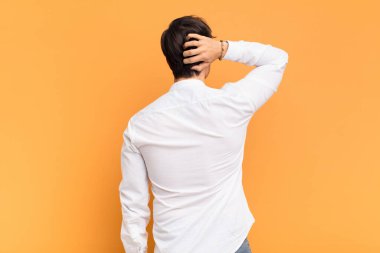 Genç yakışıklı adam düşünüyor ya da şüphe ediyor, kafasını kaşıyor, şaşkın ve kafası karışık hissediyor, arkaya ya da arkaya bakıyor.