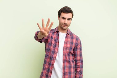 Gülümseyen ve arkadaş canlısı görünen bir adam, dört ya da dört numarayı gösteriyor, eli önde, geriye doğru sayıyor.