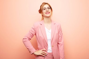 Genç ve güzel sarışın kadın mutlu bir şekilde gülümsüyor, eli kalçasında ve kendinden emin, olumlu, gururlu ve arkadaş canlısı bir tavırla. iş kavramı