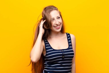 Genç sarışın kadın neşeli ve sıradan bir şekilde gülümsüyor, olumlu, mutlu ve kendinden emin bir şekilde göğüs göğüse tutuşuyor.