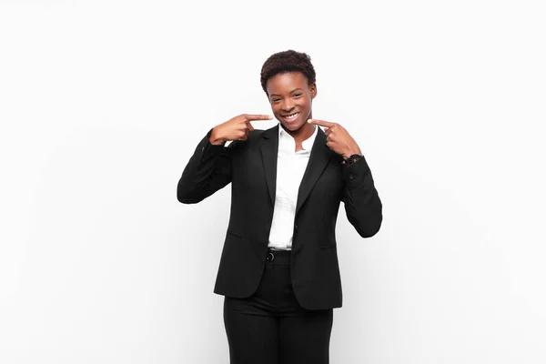 自信を持って笑顔を見せる若い黒人女性肯定的でリラックスした白い壁に対する満足した態度 — ストック写真