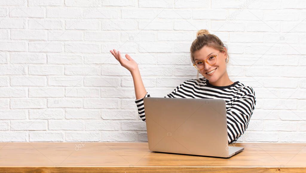 young pretty latin woman smiling proudly and confidently, feeling happy and satisfied and showing a concept on copy space sitting with her laptop