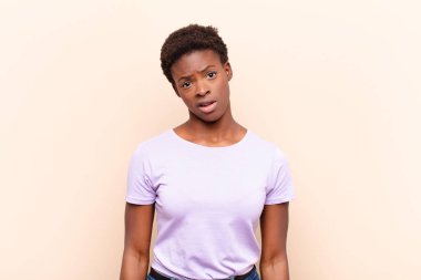 young pretty black womanfeeling puzzled and confused, with a dumb, stunned expression looking at something unexpected