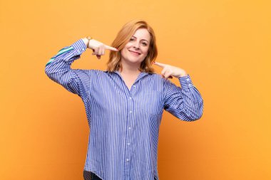 Orta yaşlı kadın kendine güvenerek gülümsüyor. Geniş bir gülümseme, pozitif, rahat, tatmin olmuş bir tavır.