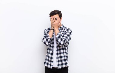 Korkmuş ya da utanmış hisseden bir adam. Gözleri yarı kapalı bir şekilde dikizliyor ya da dikizliyor.