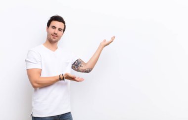 Adam gururla ve özgüvenle gülümsüyor, mutlu ve tatmin olmuş hissediyor ve fotokopi alanında bir konsept gösteriyor.