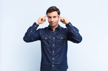 Genç yakışıklı adam konsantre olmuş ve bir fikir üzerinde kafa yoruyor, mavi duvara karşı bir meydan okuma ya da probleme bir çözüm hayal ediyor.