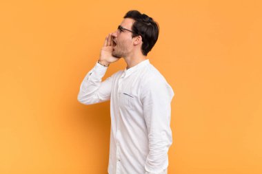 Genç yakışıklı profil görüntüsü, mutlu ve heyecanlı görünüyor, bağırıyor ve kenardaki boşluğu kopyalamak için arıyor