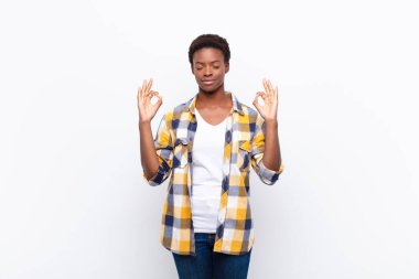 Genç ve güzel siyah kadın konsantre ve meditasyon yapıyor, tatmin oluyor ve rahatlıyor, düşünüyor ya da bir seçim yapıyor.