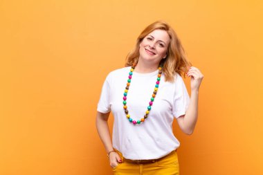 Orta yaşlı bir kadın neşeli ve tesadüfen gülümsüyor, olumlu, mutlu ve kendinden emin bir bakışla göğüs göğüse tutuşuyor.