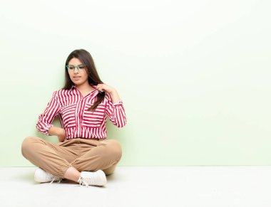 Genç, güzel bir kadın kendini stresli, endişeli, yorgun ve hayal kırıklığına uğramış hissediyor. Boynunu çekiştiriyor. Yerde oturmaktan sıkılmış görünüyor.