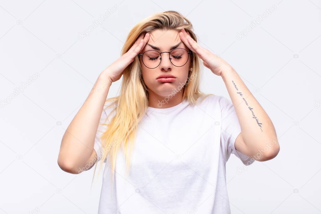 young pretty blonde woman looking stressed and frustrated, working under pressure with a headache and troubled with problems against white wall