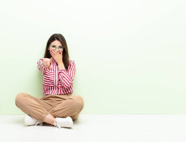Genç ve güzel bir kadın sana gülüyor, kamerayı gösteriyor ve seninle dalga geçiyor ya da yerde oturuyor.