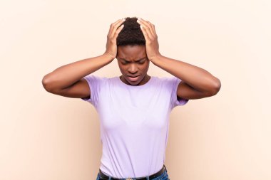 young pretty black womanfeeling stressed and frustrated, raising hands to head, feeling tired, unhappy and with migraine clipart