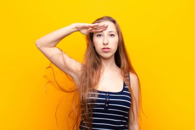 Genç sarışın kadın saygı göstererek, onur ve vatanseverlik adına kameraya selam veriyor.