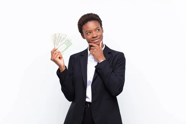 幸せそうな表情をした若い黒人女性が顎を手に銀行券を手に — ストック写真