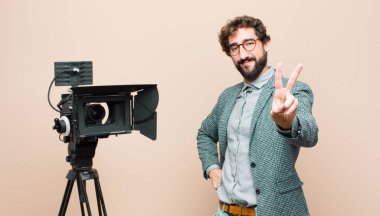 Televizyon sunucusu gülümsüyor ve mutlu görünüyor, arkadaş canlısı ve memnun, zafer ya da barış işareti yapıyor.