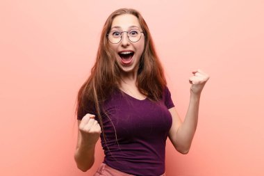 Genç sarışın kadın mutlu, şaşırmış ve gururlu, bağırıyor ve başarıyı büyük bir gülümsemeyle kutluyor.