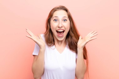 yound blonde woman feeling shocked and excited, laughing, amazed and happy because of an unexpected surprise clipart