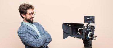 TV sunucusu kameraya çapraz kollar ve mutlu, kendinden emin, tatmin olmuş bir ifade ile gülümsüyor.