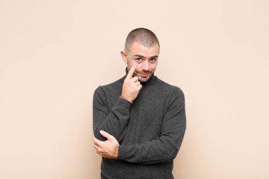 Genç yakışıklı adam sana göz kulak oluyor, güvenmiyor, izliyor, tetikte ve düz duvara karşı tetikte.