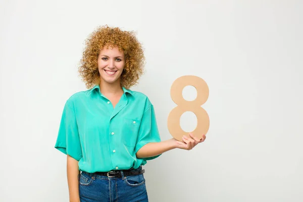 young pretty afro woman excited, happy, joyful, holding a number 8.