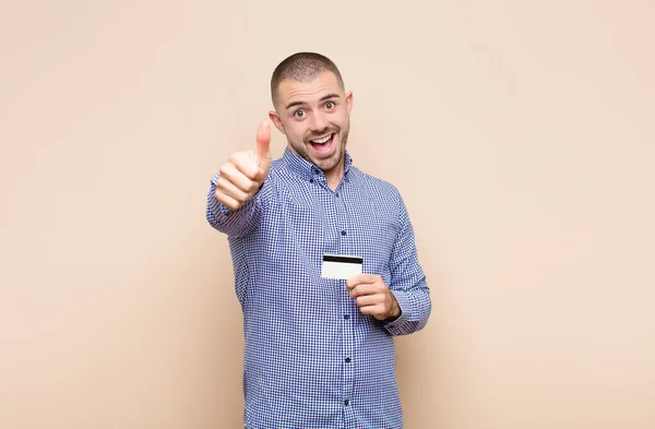 若いハンサムな男は誇りを感じます 屈託のない 自信と幸せ クレジットカードで親指で積極的に笑顔 — ストック写真