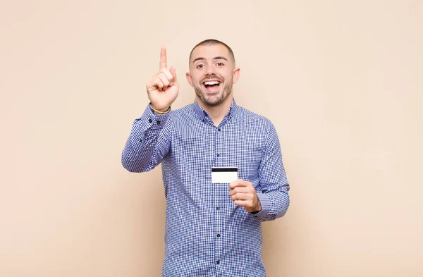 アイデアを実現した後に幸せと興奮の天才のように感じる若いハンサムな男 陽気に指を上げる ユーレカ クレジットカードで — ストック写真
