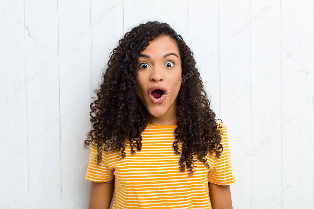 young latin woman looking very shocked or surprised, staring with open mouth saying wow