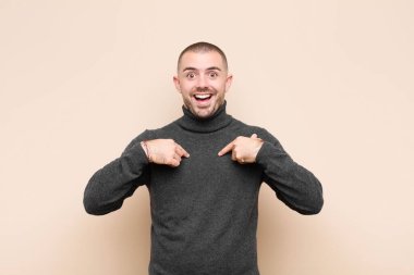 Genç yakışıklı adam mutlu, şaşırmış ve gururlu hissediyor. Heyecanlı ve şaşkın bir şekilde duvara bakıyor.