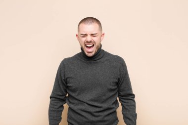 Genç yakışıklı adam agresif bir şekilde bağırıyor, sinirli, sinirli, öfkeli ya da sinirli görünüyor, düz duvara karşı hayır diye bağırıyor.