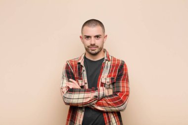 Genç, yakışıklı bir adam hayal kırıklığına uğramış, hayal kırıklığına uğramış, ciddi görünüyor, kızgın ve kollarını düz duvara dayamış.