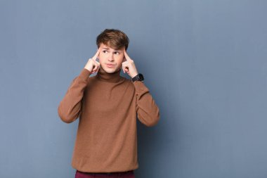 Genç sarışın adam bir fikre odaklanmış ve kafa yoruyor, bir meydan okumaya ya da duvara karşı izole edilmiş bir probleme çözüm hayal ediyor.