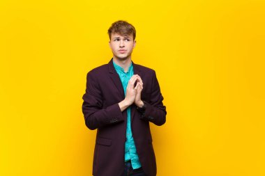 Genç sarışın adam entrikalar ve komplolar kuruyor, sinsi hileler ve hileler düşünüyor, kurnazlık ve ihanet, yassı duvara karşı izole edilmiş.