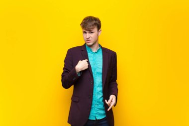 Kafası karışmış, kafası karışmış ve kendine güveni olmayan genç sarışın bir adam kendini gösterip kim olduğumu soruyor, ben mi? Düz duvara karşı izole