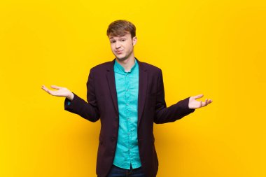 Genç sarışın adam şaşkın ve şaşkın hissediyor, doğru cevap veya karardan emin değil, düz duvara karşı izole edilmiş bir seçim yapmaya çalışıyor.