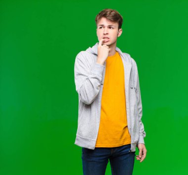 Şaşırmış, gergin, endişeli ya da korkmuş bakışları olan genç sarışın adam, kroma tuşuna karşı kopya boşluğuna bakıyor.