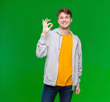 Genç sarışın adam kendini mutlu, rahat ve tatmin olmuş hissediyor. Onayını iyi bir hareketle gösteriyor. Krom anahtarın duvarına gülümsüyor.