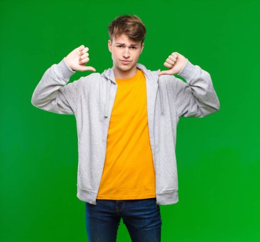 Genç sarışın adam üzgün, hayal kırıklığına uğramış ya da kızgın görünüyor, anlaşmazlık içinde parmaklarını gösteriyor, kroma anahtarına karşı hayal kırıklığına uğramış hissediyor.