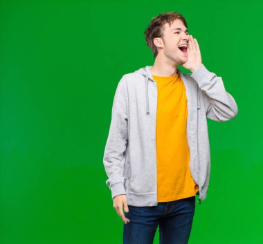 Genç sarışın adam profili, mutlu ve heyecanlı görünüyor, bağırıyor ve Chroma anahtar duvarına karşı alan kopyalamak için çağırıyor