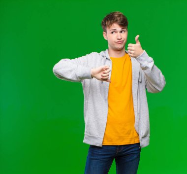 Genç sarışın adam kafası karışık, bilgisiz ve kararsız hissediyor, iyi ve kötü seçenekleri farklı seçeneklerle tartıyor ya da kroma anahtar duvarıyla karşılaştırıyor.