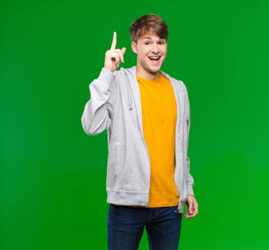 Genç sarışın bir adam bir fikri fark ettikten sonra mutlu ve heyecanlı bir dahi gibi hissediyor, neşeli bir şekilde parmağını kaldırıyor, eureka! Krom tuş duvarına karşı